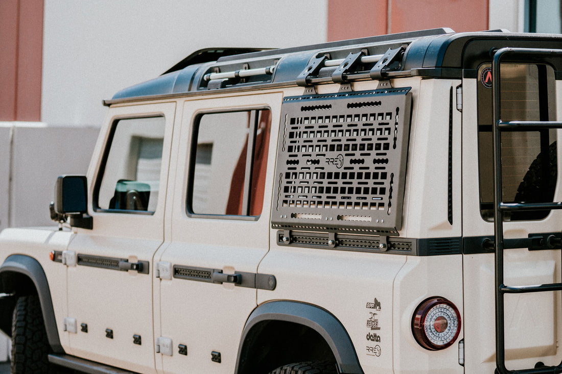 A Black Exterior cargo carrier made by Rough Road Equipment with the RRE logo stamped into it, shown on an Ineos Grenadier. Featuring three different attachment points for various systems like L-track (Airline Track), MOLLE, and Carrage bolt. Show with the optional LeTech roof rack attachment mount and the LeTech roof rack. MaxTraxx not included. 